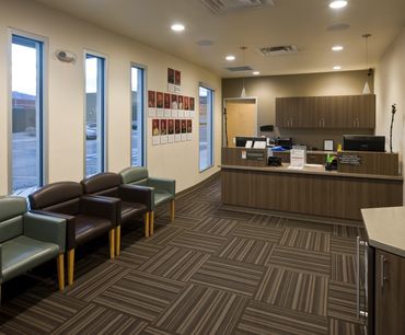 Modern healthcare reception area with striped carpet, wood finishes, and warm ambient lighting.