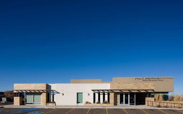Modern single-story physical therapy building with clean lines, stone accents, and deep blue sky.