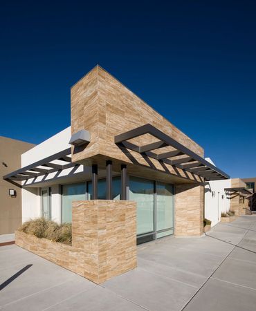 Modern building corner with stone façade, steel canopy, and clean geometric architectural lines.