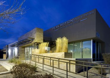 Modern physical therapy building illuminated at dusk with stone accents and architectural lighting.
