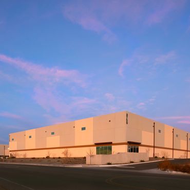 Modern warehouse exterior with clean lines and soft sunset lighting against a pastel sky.