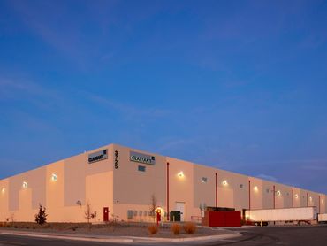Modern warehouse building illuminated at dusk with loading docks and minimal architectural detailing