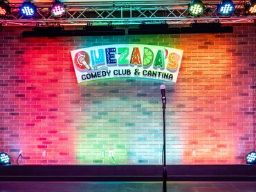Quezada’s Comedy Club and Cantina stage with colorful lighting and brick backdrop at Santa Ana Star.