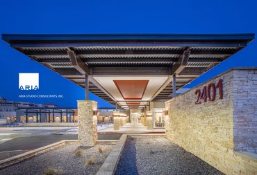 Covered entryway at Senior Care facility with stone walls, steel canopy, and warm evening lighting.