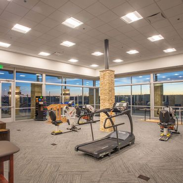 Spacious fitness room with treadmills, exercise bikes, and large windows for natural light.