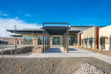 Modern senior care facility with steel canopy walkway, stone detailing, and desert landscaping.