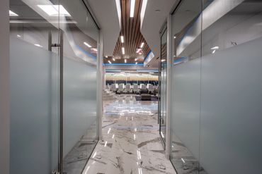 Glass hallway with marble floors and wood ceiling leading to meeting area at SC3 International HQ.