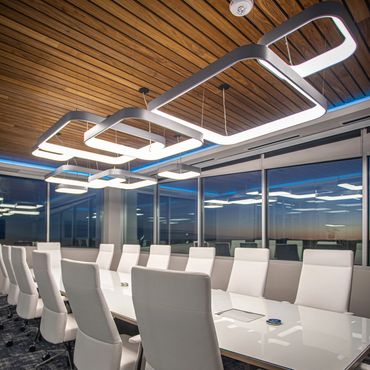 Conference room with white chairs, wood ceiling, and modern lighting at SC3 International HQ.