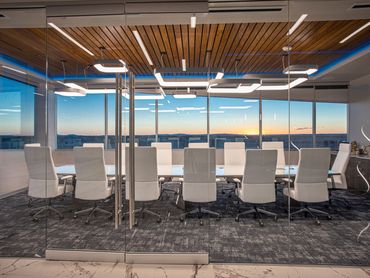 Glass-walled conference room with white chairs and sunset view at SC3 International HQ.
