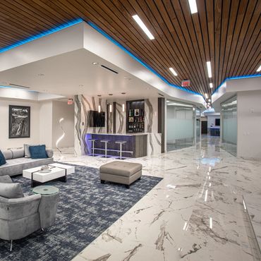 Lobby at SC3 HQ with wood slat ceiling, custom LED lighting, and marble floors.
