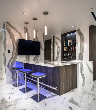 Modern bar at SC3 HQ with marble walls, LED lighting, and sleek wood cabinetry.