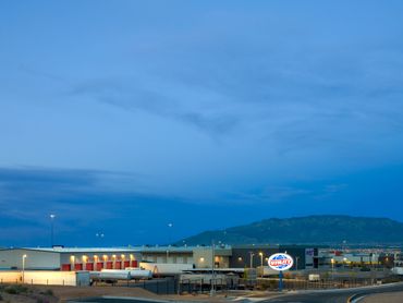 Utility Trailer facility at dusk with illuminated signage and Sandia Mountains in the distance.