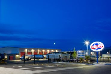 Utility Trailer service facility at dusk with illuminated logo and red service bay doors.