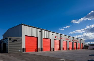 Warehouse with bold red service bays and metal siding under a bright blue sky.