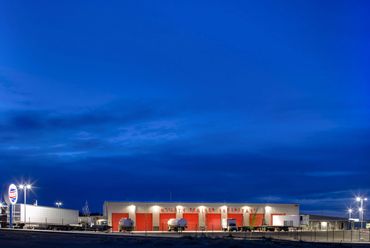 Utility Trailer facility with illuminated red service bays and trucks parked at night.