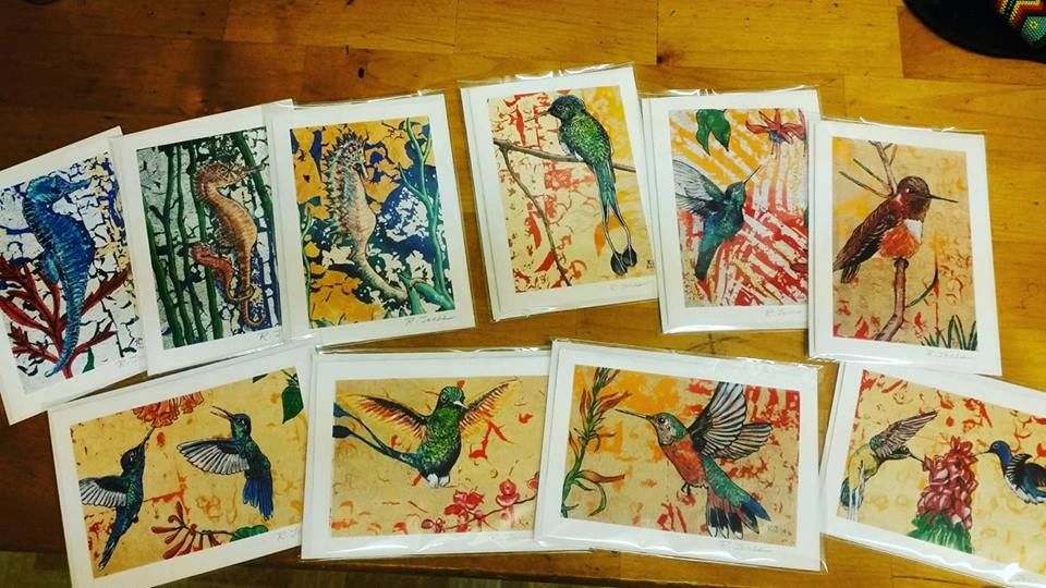 Ten greeting cards of hummingbirds, and sea horses on a table.