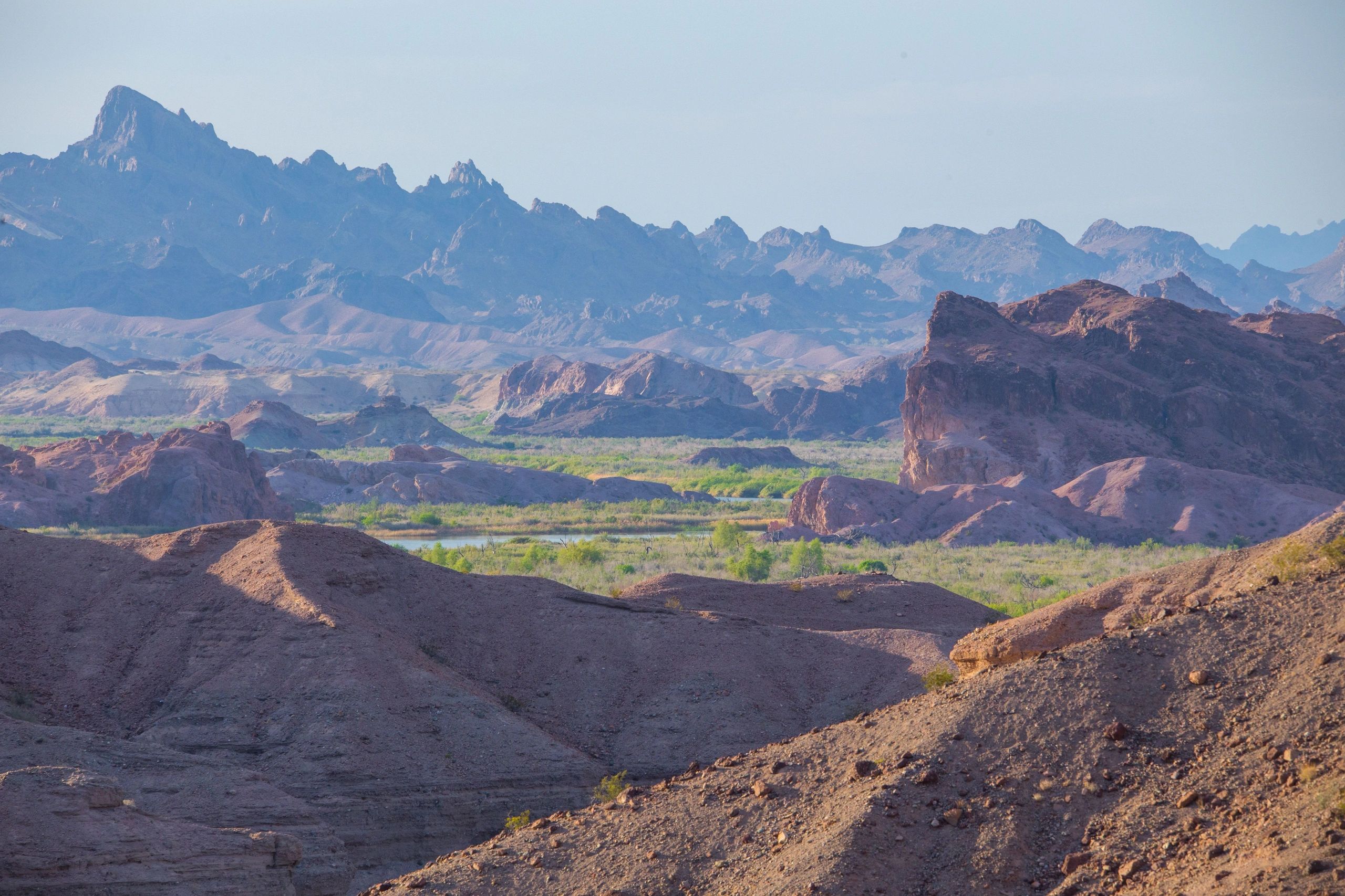 Rocky terrain with distant mountains under clear sky.