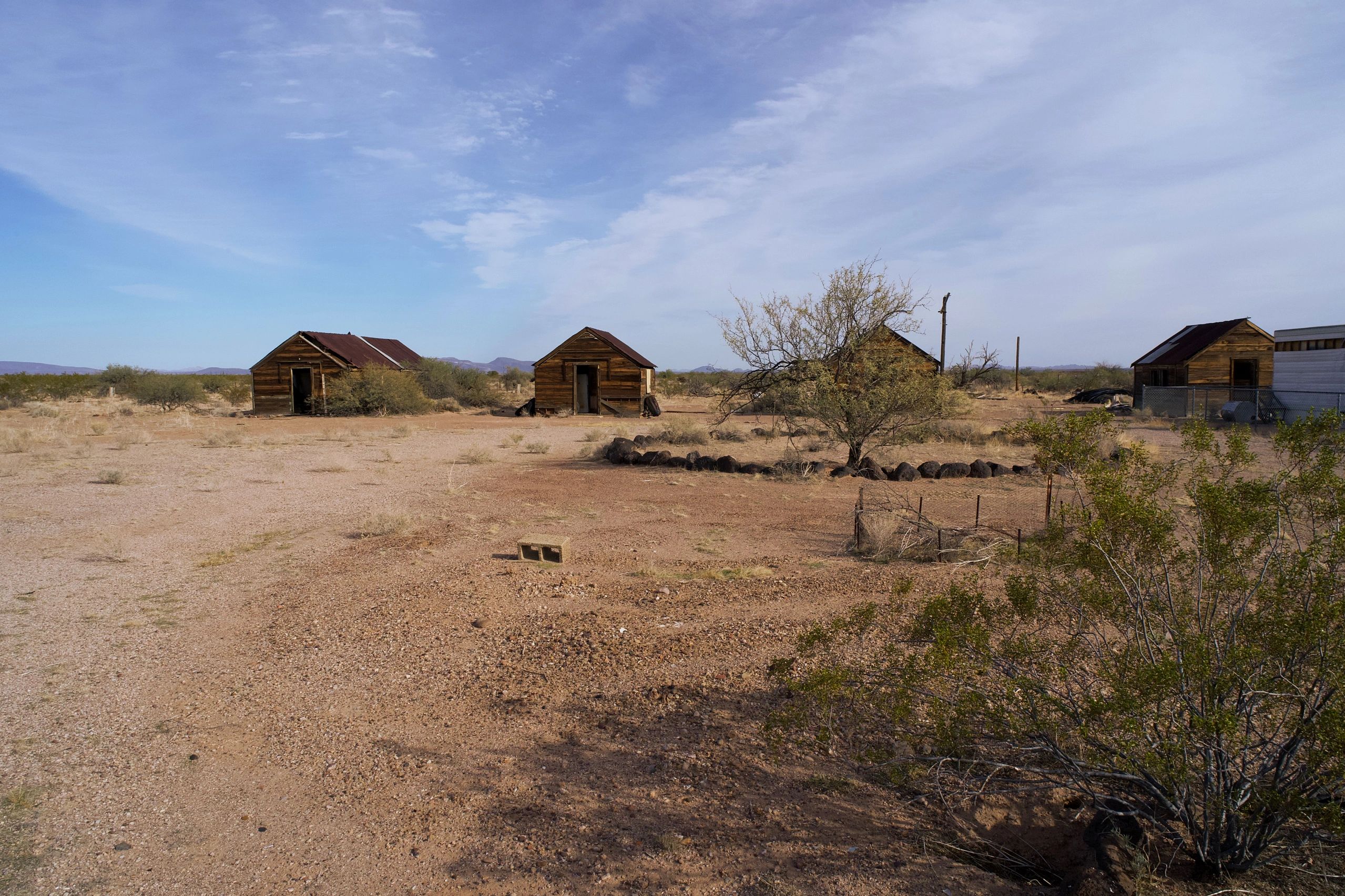 Four small wooden houses in a desert landscape.