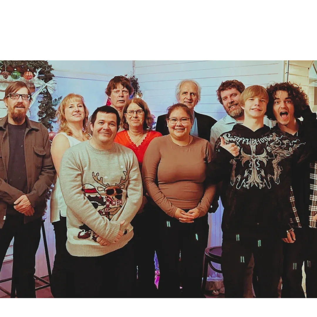 A diverse group of people posing happily indoors with holiday decorations.