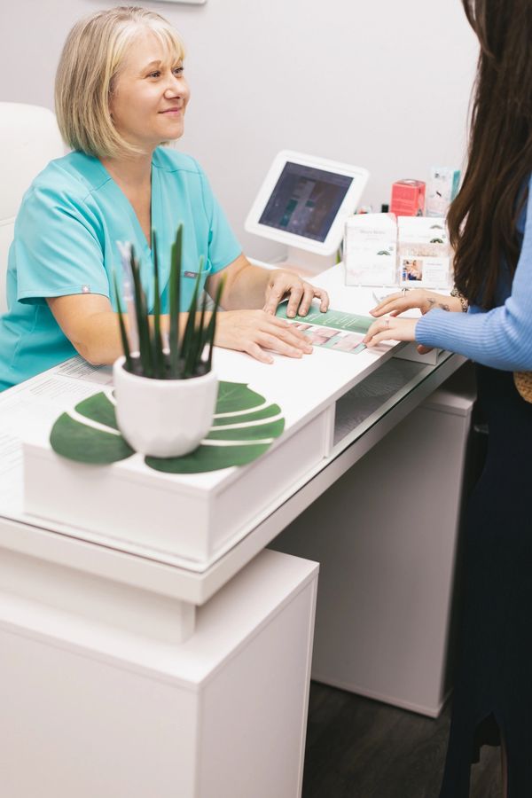 Professional image of Nicky, owner, with client at the front desk of Supernatural Esthetics.