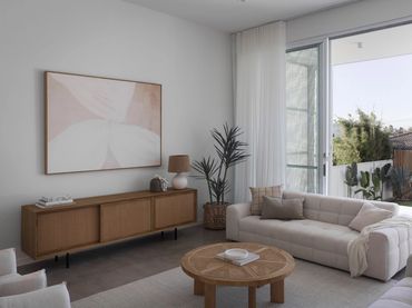 Minimalist living room with neutral tones, wooden furniture, and natural light.