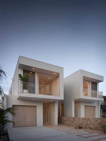 Modern twin homes with clean lines and minimalistic design under a clear sky.
