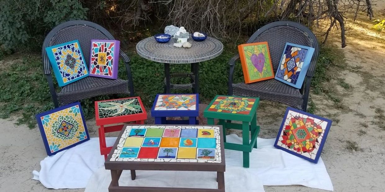 Outdoor display of colorful mosaic art on furniture and frames.