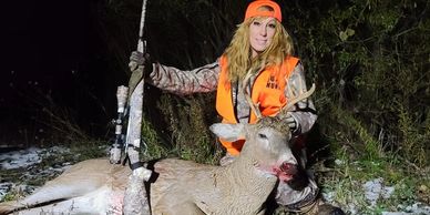 A girl with a deer while hunting.