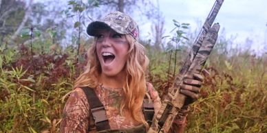 A smiling girl with a shotgun.