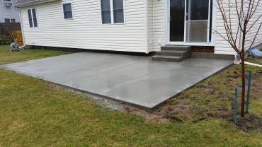 Newly poured concrete patio outside a house.
