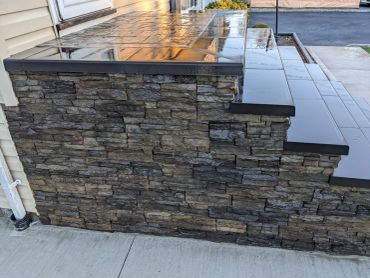 Wet stone wall and tiled steps outside a house.