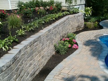 Neatly landscaped garden with retaining wall and pool.