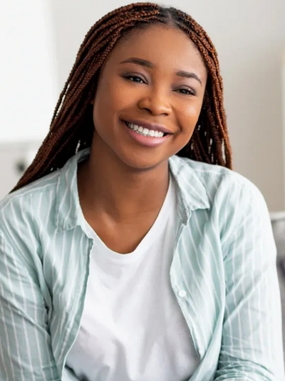Smiling woman with braided hair wearing a white shirt and light striped jacket.