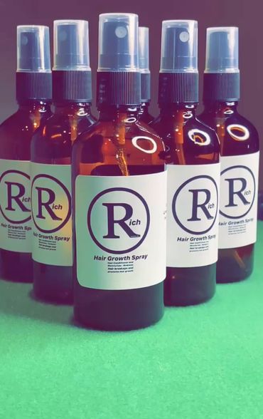 Bottles of Rich Hair Growth Spray arranged on a green surface.