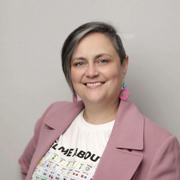 Smiling woman wearing a pink coat and creative earrings.