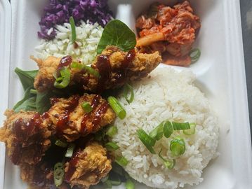 Fried chicken, white rice, kimchi, and salad in a container.