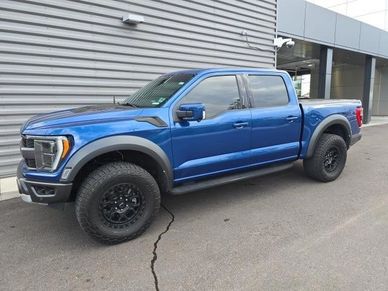 Blue Ford Raptor pickup truck parked outside a building.