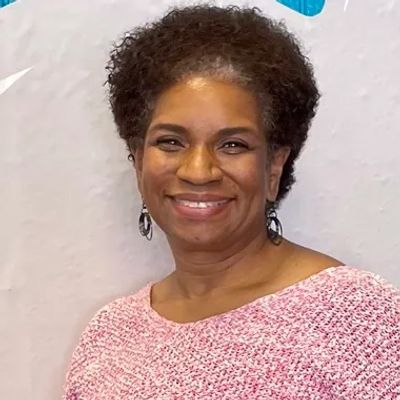 Smiling woman in a pink textured sweater against a light background.