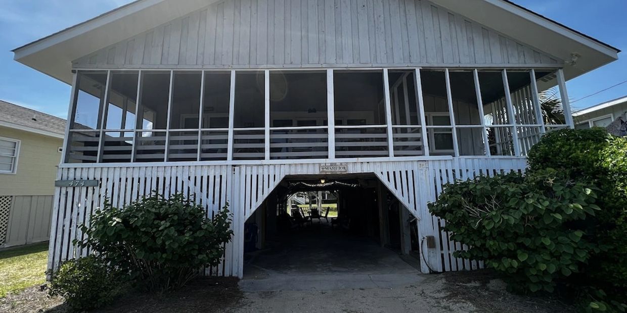White screened porch house with carport underneath.