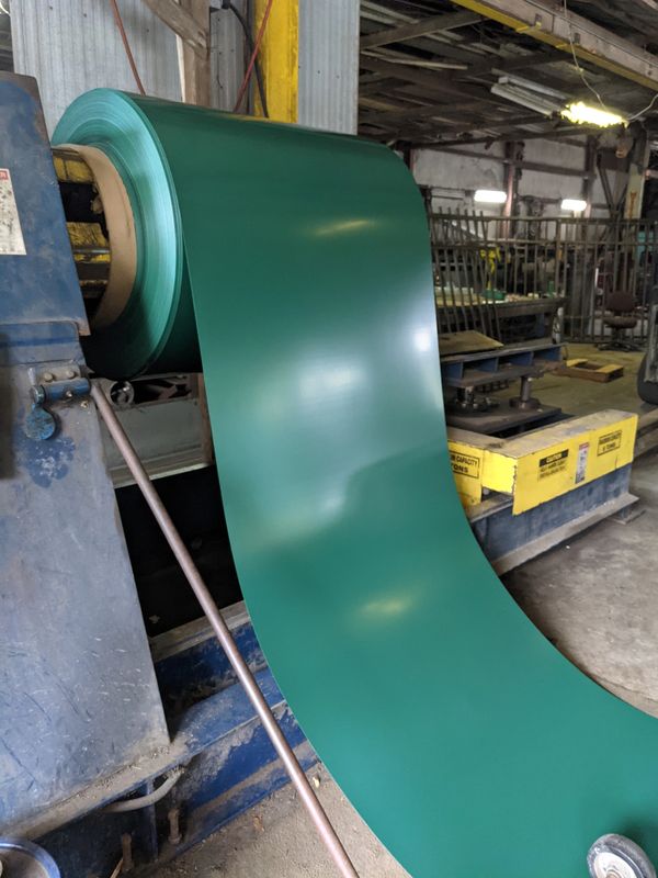 Roll of green metal sheet in an industrial setting.