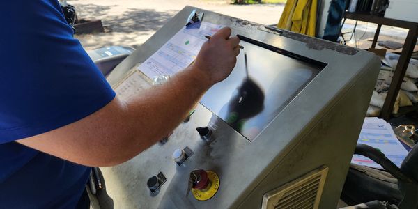 Person operating a control panel with touchscreen and buttons.