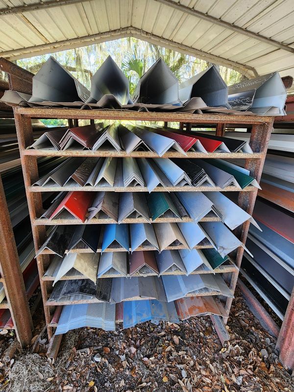 Rusty metal rack holding various colored metal angle bars.