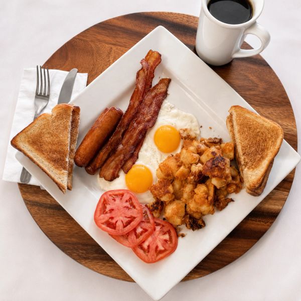 Classic breakfast with eggs, bacon, sausage, toast, tomatoes, and coffee.