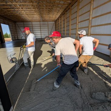 Workers smoothing concrete inside a large wooden structure.