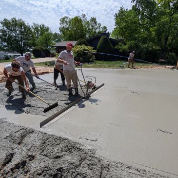 Workers pouring and leveling concrete outdoors.