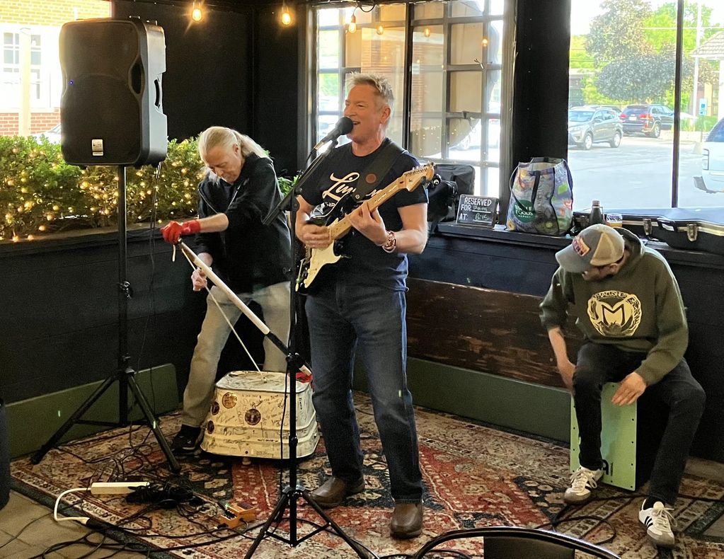 Three men performing live music indoors with instruments.