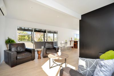 Modern living room with leather chairs and a dining area in Whangaparaoa.
