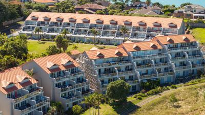 A complex of modern apartment buildings with orange tiled roofs in Gulf Harbour.