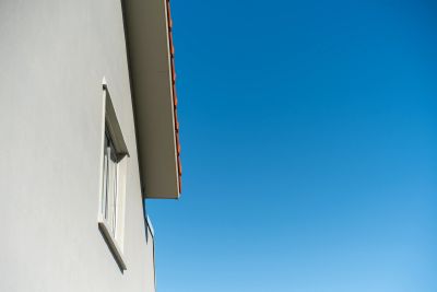 Side view of a building with a window against a clear blue sky.