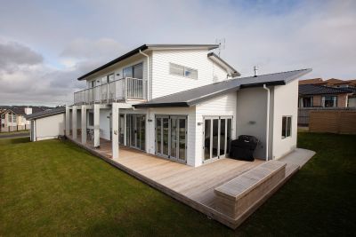 Modern two-story house with white exterior and wooden deck.